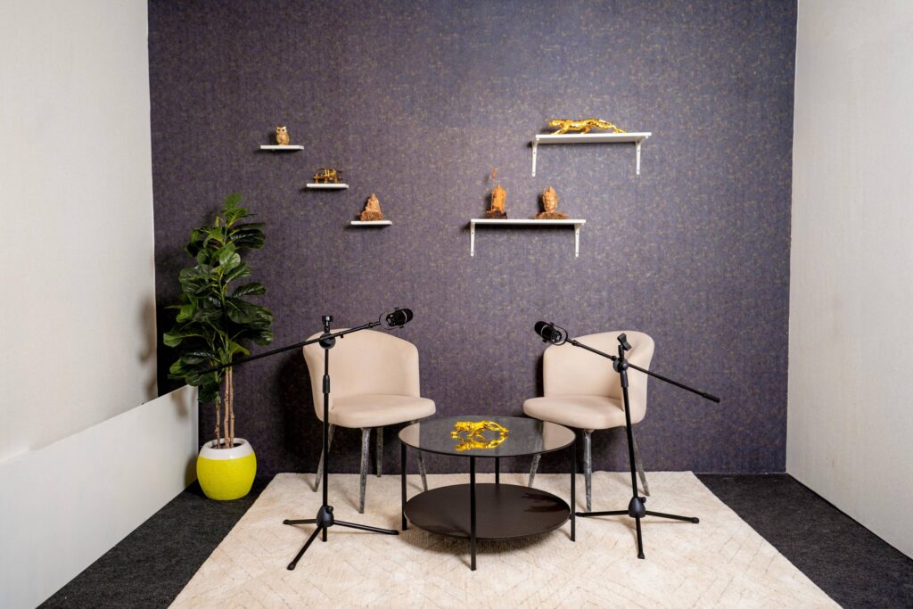 Two-person podcast studio with layered shelf backdrop and cozy seating at Ollar Studios Mumbai